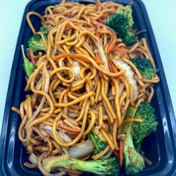 Vegetarian chow mein noodles with broccoli, carrots, and onions in a black takeout container.