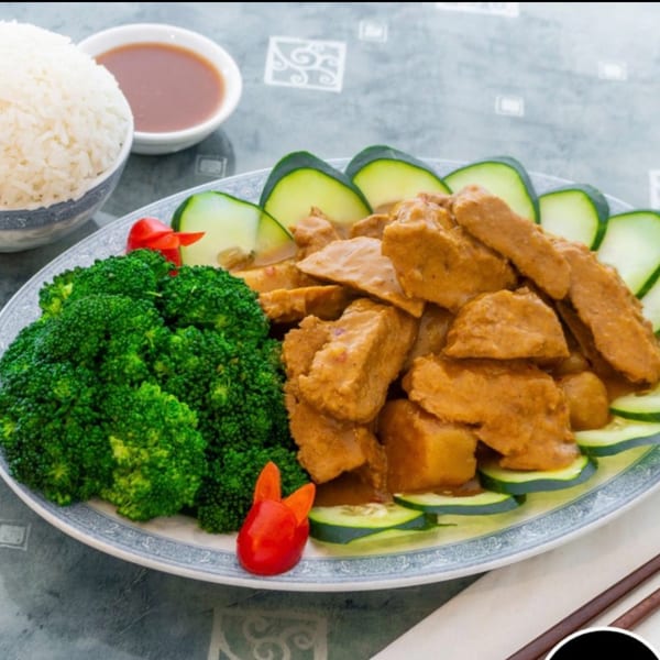 Vegetarian dish with brown-sauced protein, broccoli, cucumber slices, rice, and dipping sauce.